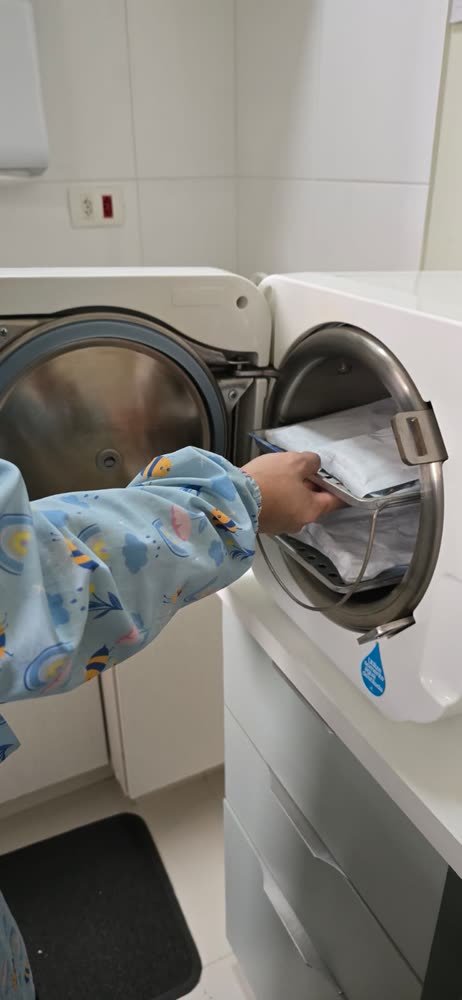 Profissional da Acássia colocando instrumentais lacrados na autoclave da clínica